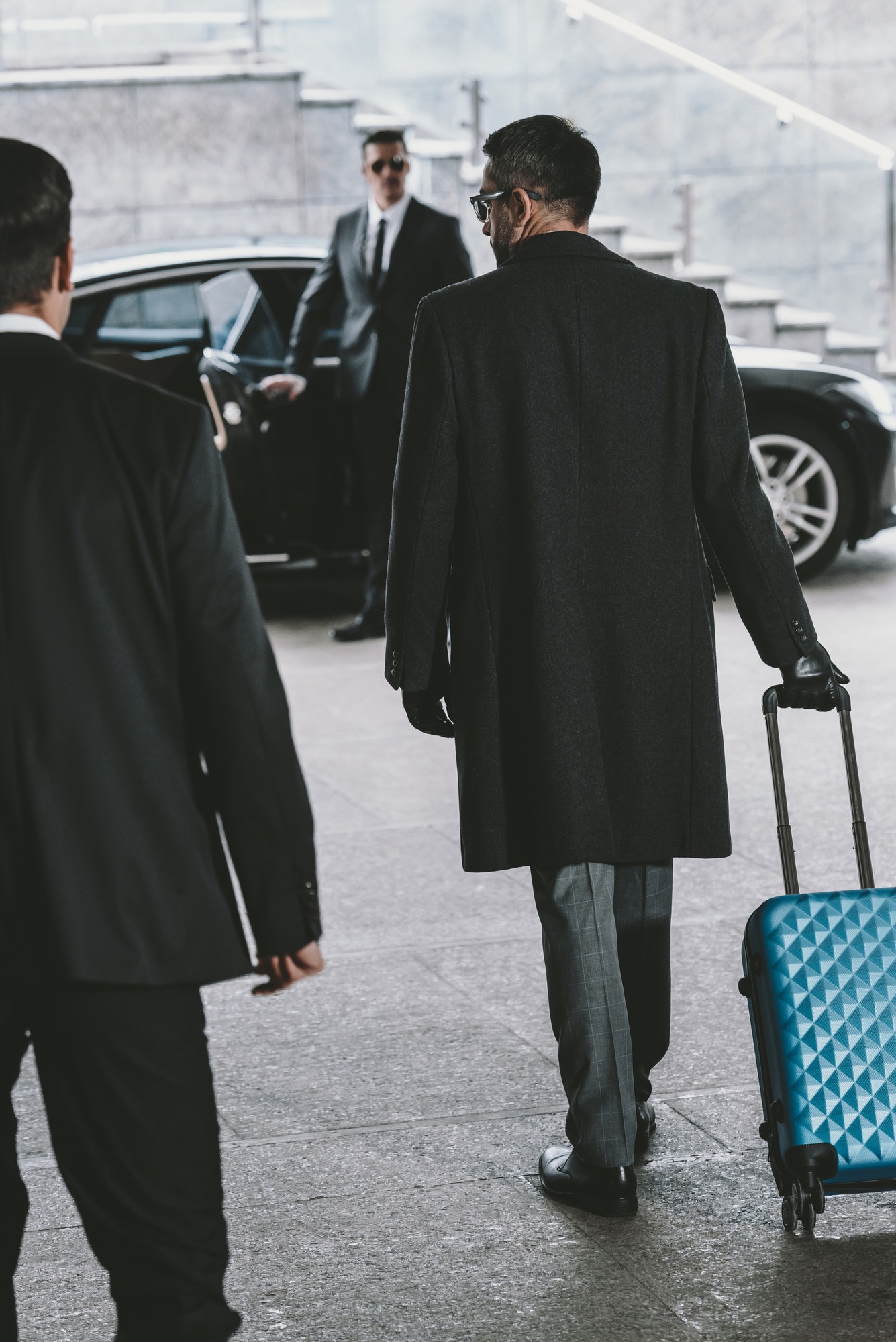 businessman-going-with-blue-travel-bag-to-car